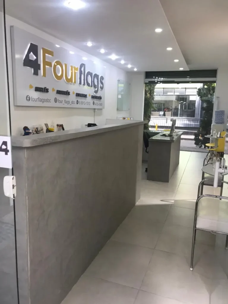 Corredor interno e recepção da FourFlags Language Center em São Bernardo do Campo, com balcão de atendimento cinza e painel iluminado da escola.