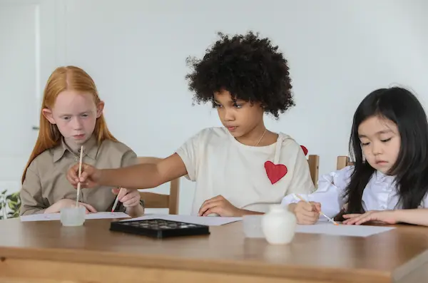 Crianças numa mesa com livros em um ambiente de escola ilustrando o curso de inglês para crianças da fourflags
