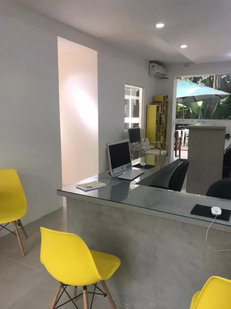 Área de atendimento e recepção da FourFlags São Bernardo do Campo, com mesas de vidro, computadores para suporte ao aluno e vista para área externa.
