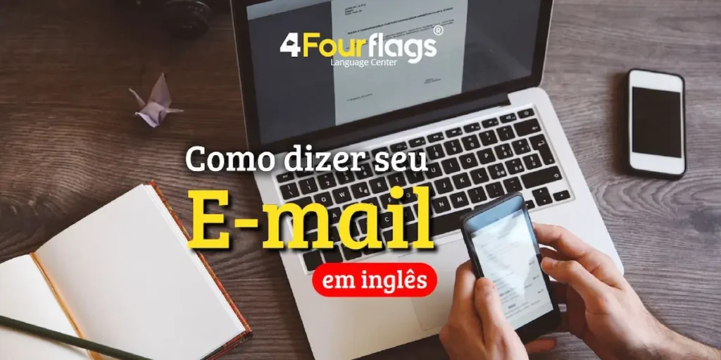 Dica de inglês: imagem ilustrativa para blog com o título 'Como dizer seu E-mail em inglês', mostrando uma pessoa utilizando o celular em frente a um computador em um ambiente de trabalho ou estudo. Marca 4 Four Flags Language Center.
